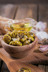 Grilled olives with garlic, olive oil and spices on wooden background