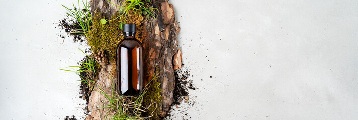 Beauty natural background with bark tree, tiny mosses and grass of organic cosmetic products in glass brown bottle. Flat lay,
