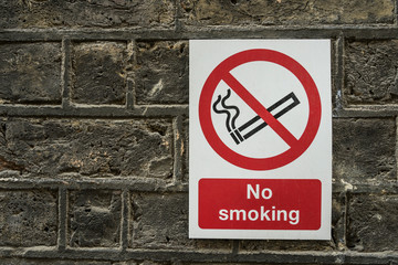 No smoking sign on a old stone wall.