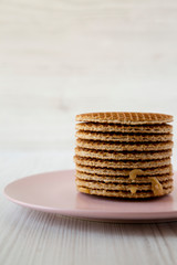 Stack of homemade Dutch stroopwafels with honey-caramel filling on a pink plate, side view.