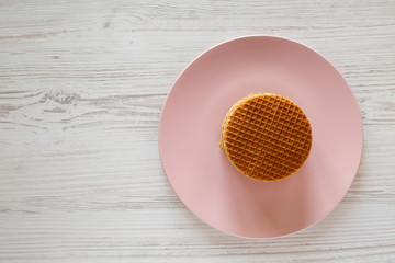 Stack of homemade Dutch stroopwafels with honey-caramel filling on a pink plate, overhead view. Flat lay, from above, top view.