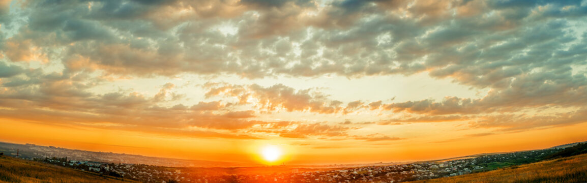Sunrise or sunset upon a city. Warm Cloudy sky and sun panorama.