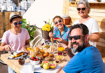 Happy breakfast for caucasian family. Outdoor in the terrace. Healthy eating. Fresh fruit and coffee. Four people