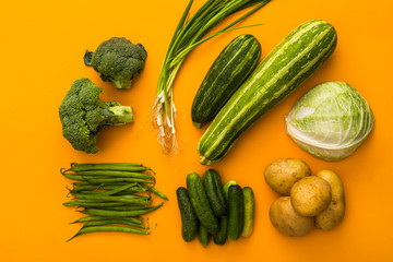 green vegetables on yellow background colorful concept, top view, potatoes, broccoli, cucumber, onion, cabbage, zucchini, beans