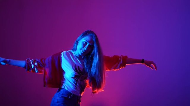 young beautiful woman dancing hip-hop, street dancing in the studio on a purple background, isolated