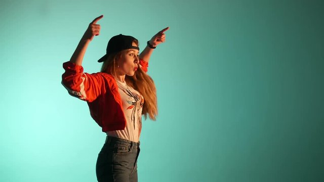 young beautiful girl in a baseball cap dancing hip hop, street dancing in the studio on a green background, isolated