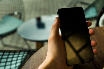 Hand holding a phone over the wooden table