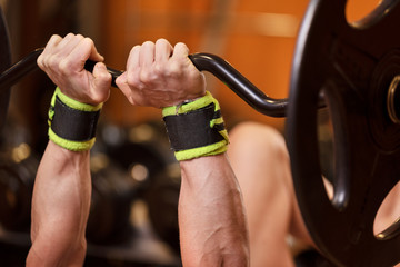 Handsome young muscular man close up, doing bench french press workout with barbell in gym .