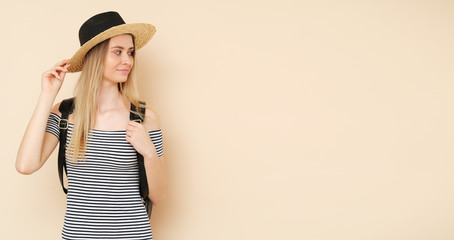 Young blonde girl with hat and black backpack on the back. Time for holiday.