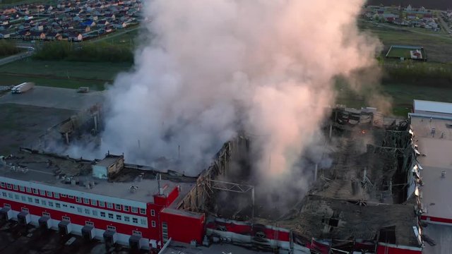 Burning industrial building with fire and huge smoke, aerial view from drone