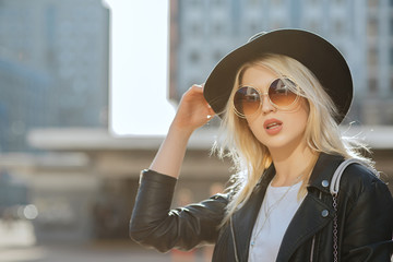 Street portrait of a glam blonde girl wearing hat and vintage sunglasses. Space for text