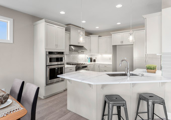 Kitchen in new elegant home with island, double ovens, pendant lights, and stainless steel...