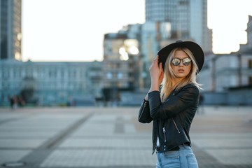Fototapeta premium Outdoor fashion portrait of a stylish blonde girl wearing hat and mirror glasses. Space for text