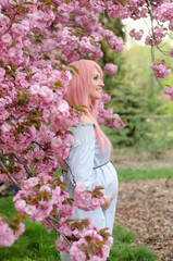 Happy pregnant woman in blue dress with pink hair