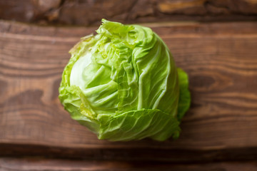 Fresh whole head of young green cabbage on wooden background.