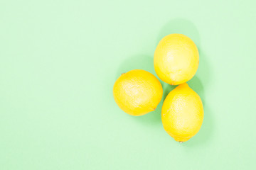 three yellow lemons on a green background.
