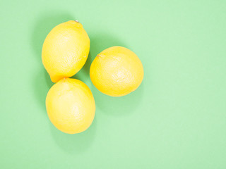 three yellow lemons on a green background.
