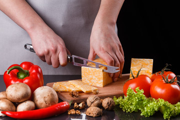 young woman slicing cheese in a gray apron