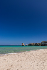 Fototapeta premium The bay of Torre dell'Orso, with its high cliffs, in Salento, Puglia, Italy. Turquoise sea and blue sky, sunny day in summer. Fine white sand beach. The stacks called the Two Sisters.