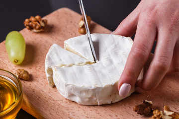 young woman slicing cheese in a gray apron
