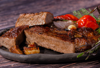 cooked steak with fried tomatoes, onions , dill and rosemary.selective focus, close-up