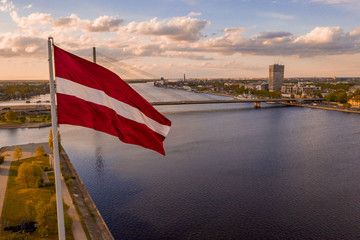 Aerial panorama of Riga city with a big Latvian flag in the foreground. Golden hour.