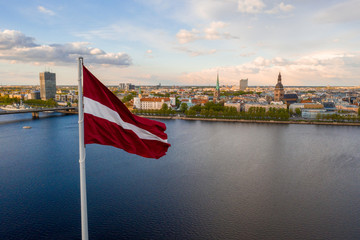 Aerial panorama of Riga city with a big Latvian flag in the foreground. Golden hour.
