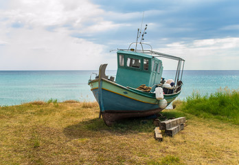 Old broken boat stays on the ground near aquamarine sea in abandoned place