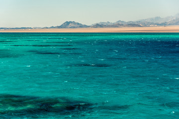 Seascape, view of the blue sea with high bald mountains in the background