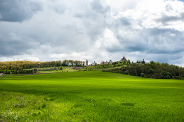 Fototapeta na wymiar Eye-catching landscape with green grass, hills and trees, cloudy sky