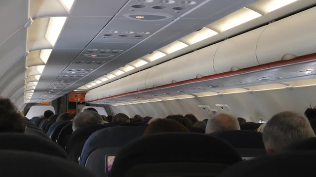 Rear view of heads of people, the aircraft passengers inside of cabin during the flight