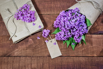 Obraz na płótnie Canvas Gift and bouquet of lilacs on a wooden table