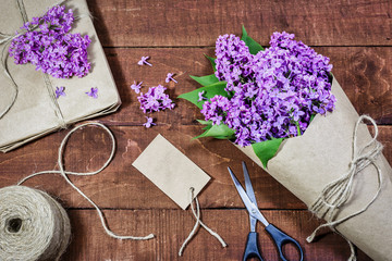 Gift and bouquet of lilacs on a wooden table