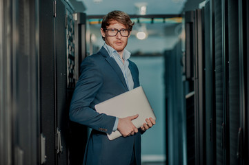 Fototapeta premium Young it engeneer business man with thin modern aluminium laptop in network server room