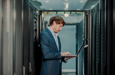  Young it engeneer business man with thin modern aluminium laptop in network server room