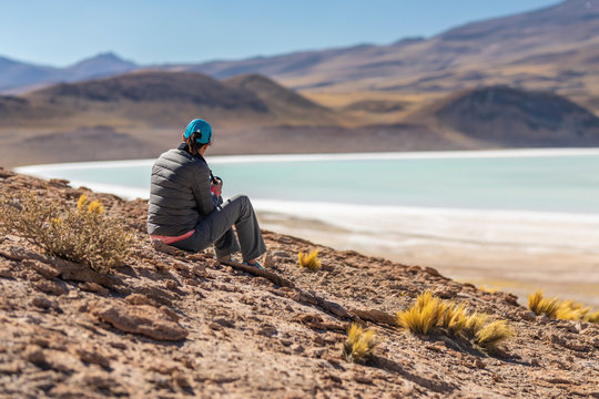 Landscape woman photographer taking photos in an amazing wilderness environment at Atacama Desert Andes mountains lagoons. A woman cut out silhouette over the awe Tuyajto Lagoon scenery at Altiplano