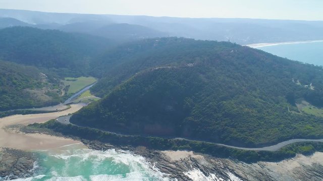 Forward flight over ocean toward Great Ocean Road and forested hills near Lorne, Victoria, Australia