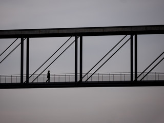 The Silhouette of A Woman Walking On A Bridge