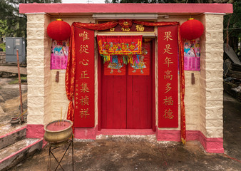 Hong Kong, China - March 7, 2019: Tai O Fishing village. Yellow and pink Taoist shrine with red main entrance door, highly decorated, at east entrance to the village.