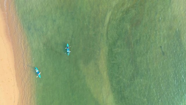 Aerial top view of kayaking around sea with shade emerald blue water and wave foam 