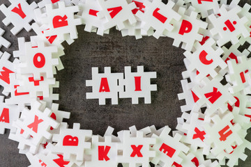 AI, Artificial Intelligence with deep learning or machine learning concept, white puzzle jigsaw building the word AI on dark black cement surrounded by other alphabets