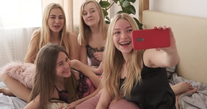 Teen girls video chatting with friends using mobile phone at slumber party