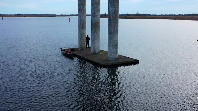 Man fishing under bridge Drone shot