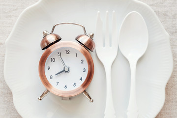 Fototapeta na wymiar A clock on the plate, Intermittent fasting diet concept