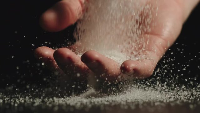 SLOW MOTION: Sugar falls on man's palm and passes through it
