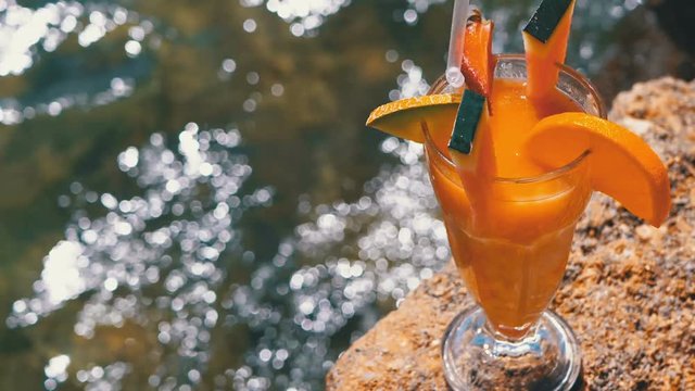 Tropical Fresh Cocktail in a Glass with Straw on the Beach of Egypt Stands on a Rock on Background of the Red Sea
