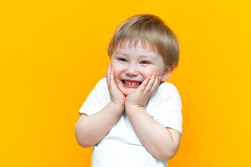portrait of cheerful little boy child three years old, standing isolated over yellow background. Looking camera. showing white teeth, smiling