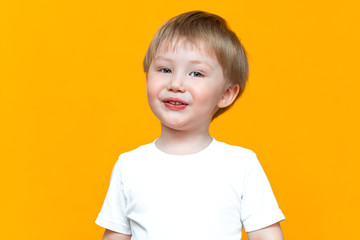 Portrait of smiling happy child 3 years old mixed race half Asian half Caucasian on yellow background with blonde hair and green eyes