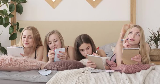 Teen girls writing shopping list in notepad at home