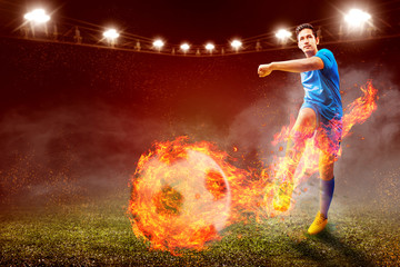 Asian football player man in blue jersey with kicking the ball with fire effect